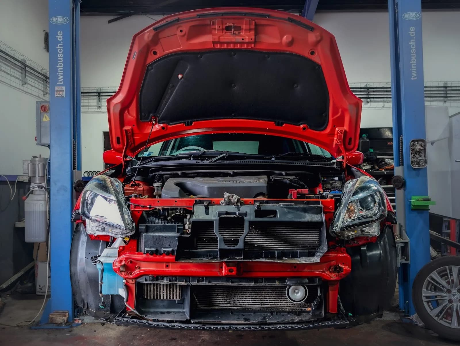 A car with the bonnet open showing the engine bay during a repair